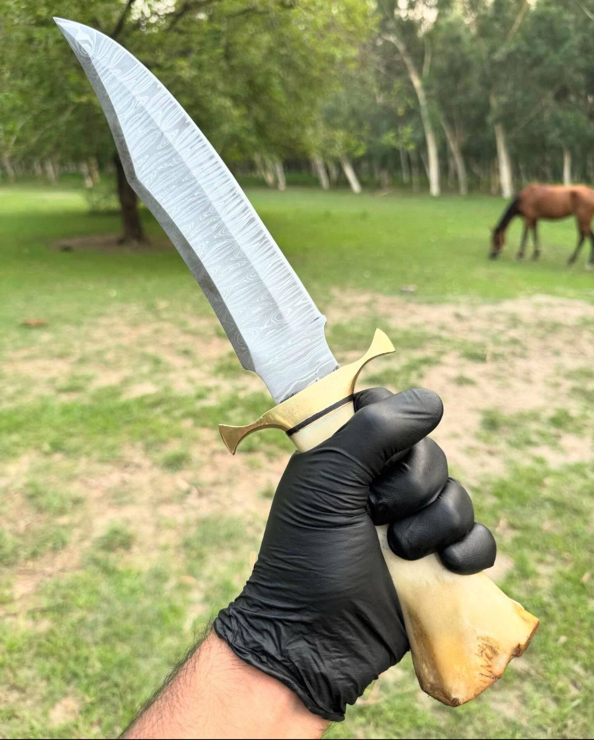 Handmade 16-inch Damascus steel Bowie knife with brass guard, camel bone handle, and leather sheath by Knives Gear Garage