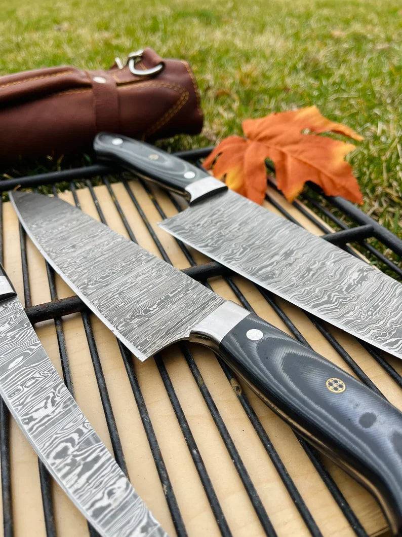 Luxury handmade Damascus steel kitchen knife set with G10 handles and steel bolsters, in a leather roll by Knives Gear Garage.