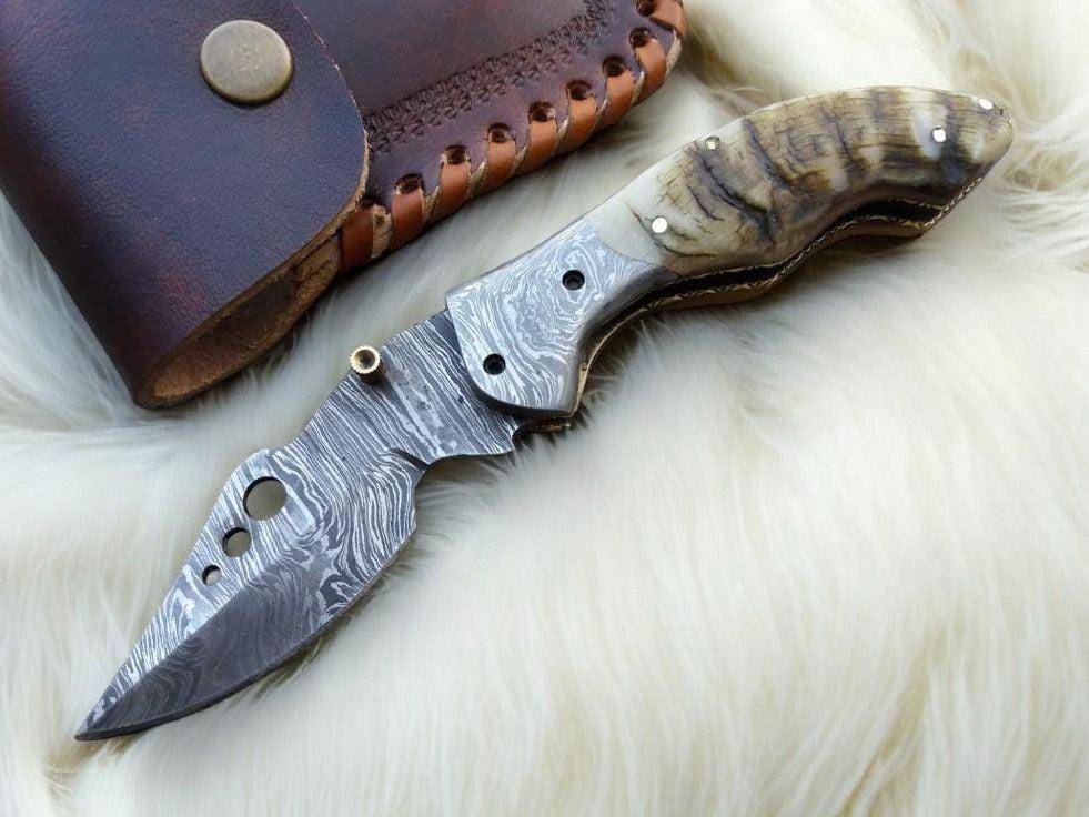 Handmade Damascus pocket knife with sheep horn handle, showcasing intricate blade design and natural horn handle detail.