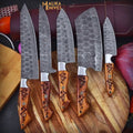 MALIKA KNIVES chef knife set with various stainless steel knives displayed on a wooden cutting board