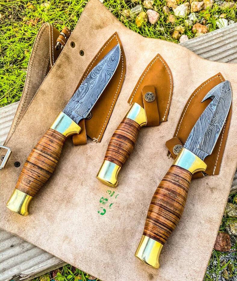 Wilderness Trio hunting knives set with Damascus steel blades, leather handles, brass guards, and leather roll by Knives Gear Garage