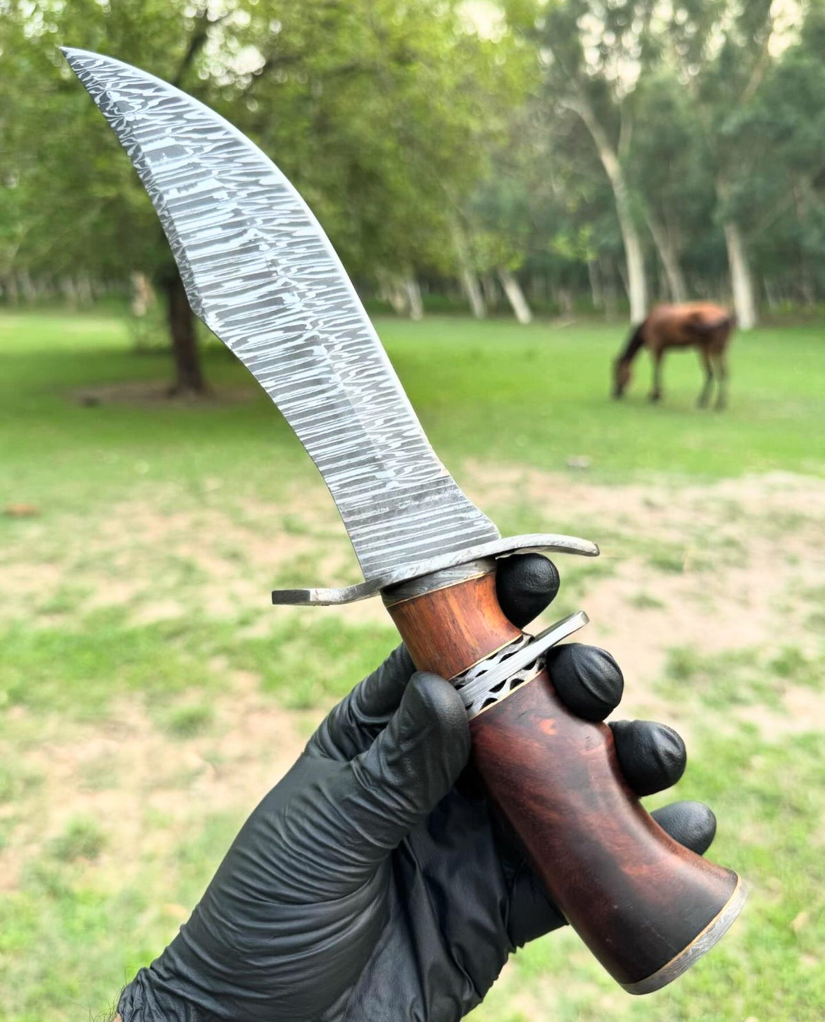 Custom handmade Damascus steel hunting Bowie knife with a leather handle and detailed blade design by Knives Gear Garage.