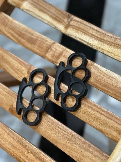 Pair of black hand-casted knuckles by CSK Forged, showing detailed textured metal finish and robust design for tactical use.
