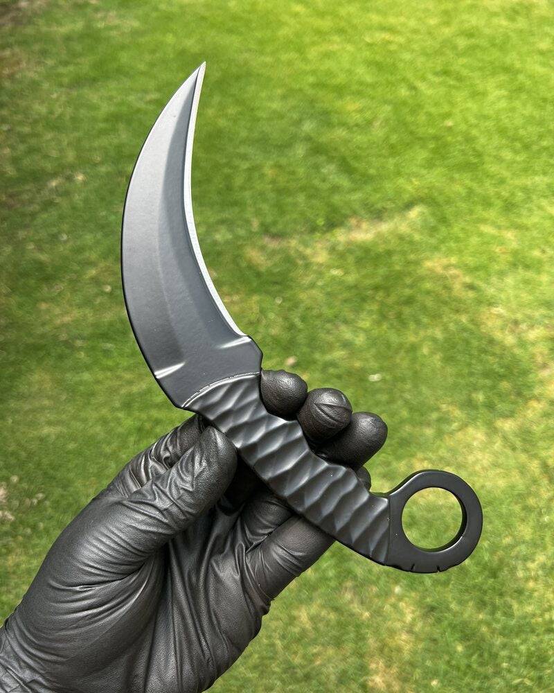 Black powder-coated Karambit knife from Knives Gear Garage, featuring a curved blade and ergonomic handle for EDC use.