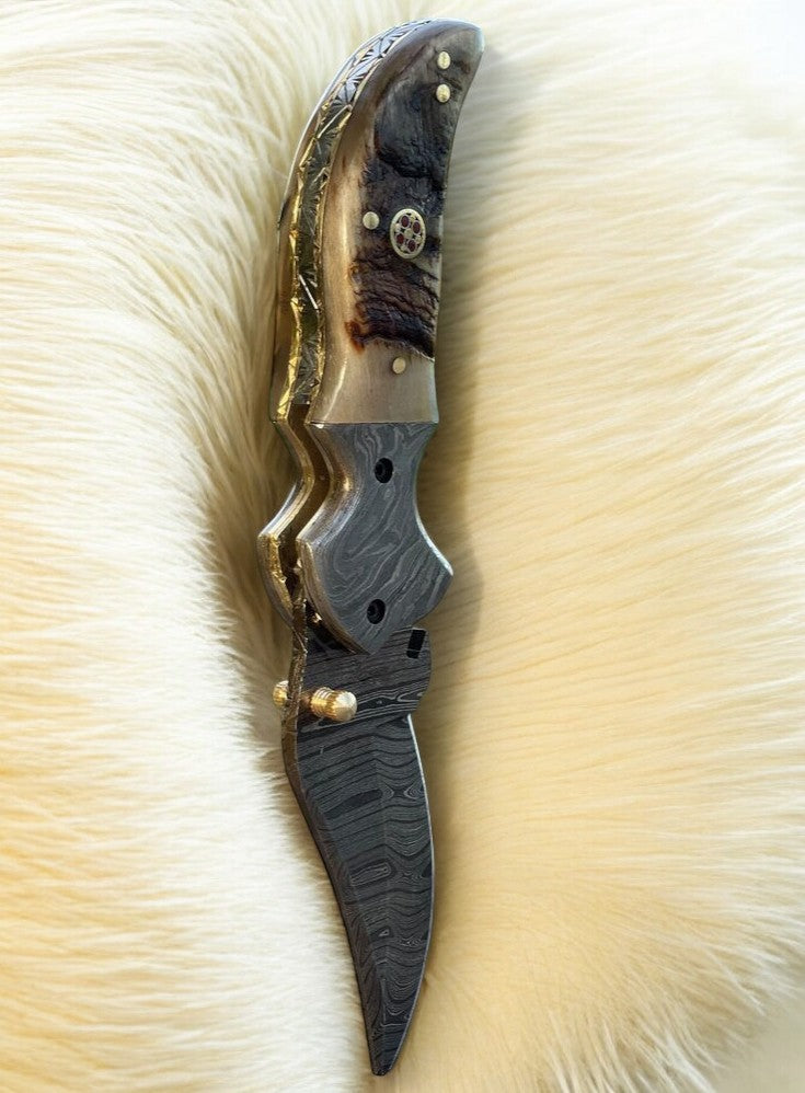 Custom handmade Damascus pocket knife with sheep horn handle, showcasing intricate blade pattern and textured handle detail.