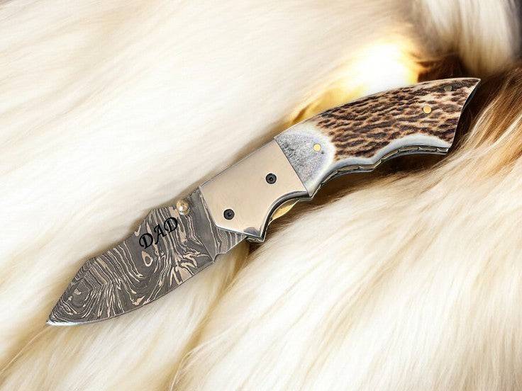 Custom handmade Damascus pocket knife with stag horn handle, featuring intricate Damascus steel blade and natural wood grip.