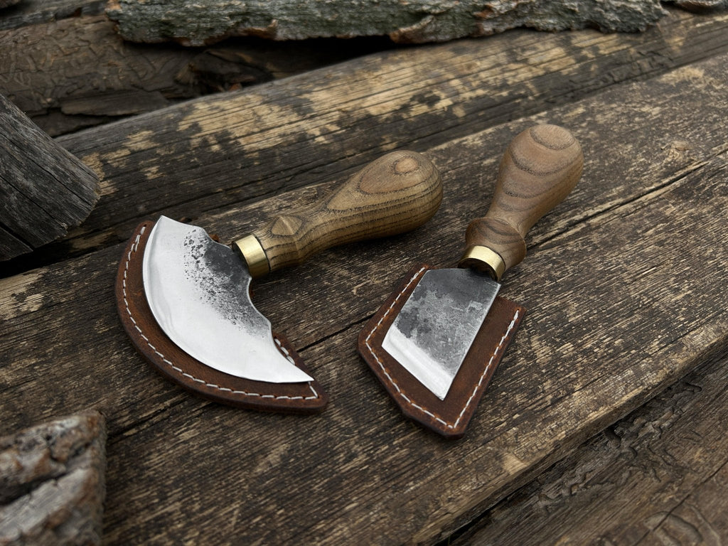 Two-piece Sharky Forged Steel Tools leather knife set with rounded and angled blades, displayed on a wooden surface.