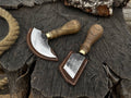 Two-piece Sharky Forged Steel Tools leather knife set with rounded and angled blades on a wooden surface.
