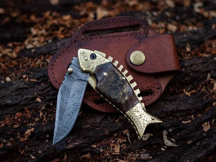 Damascus steel blade pocket folding knife with fish-shaped handle by cskforged, showcasing intricate pattern and compact design.