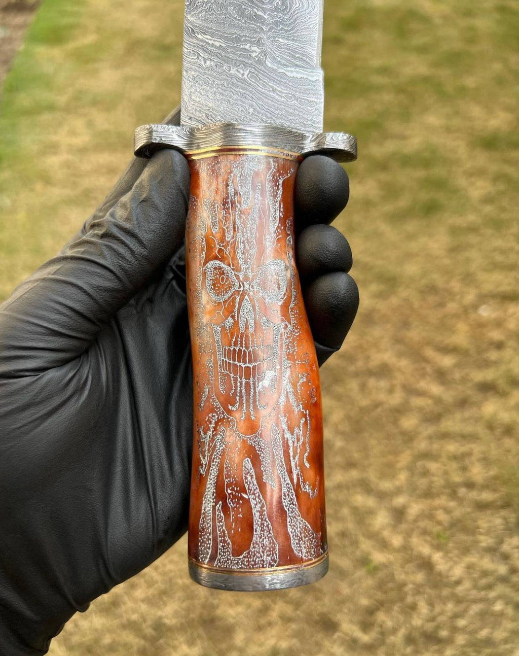 Handmade Damascus hunting knife with skull handle by cskforged, featuring a sharp blade and detailed skull design.