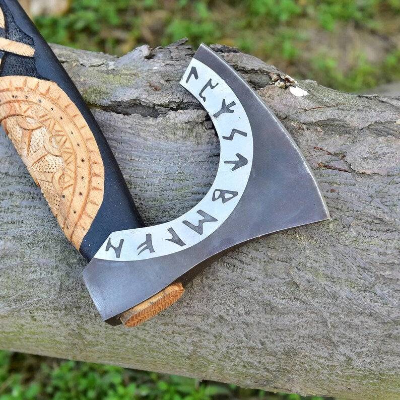 Hand-forged carbon steel Viking axe with wooden handle and leather sheath, ideal for woodworking or outdoor use.