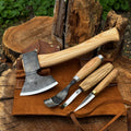 Four-piece Sharky Forged Steel Tools spoon carving set with wooden handles on a workbench, ready for wood carving projects.