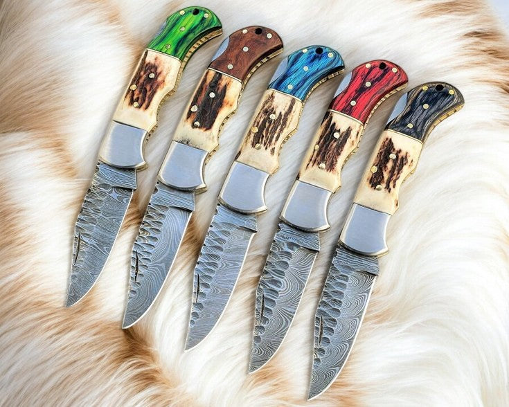 Handmade Damascus folding knife with stag and exotic wood handle, showcasing intricate blade pattern and natural wood grain.