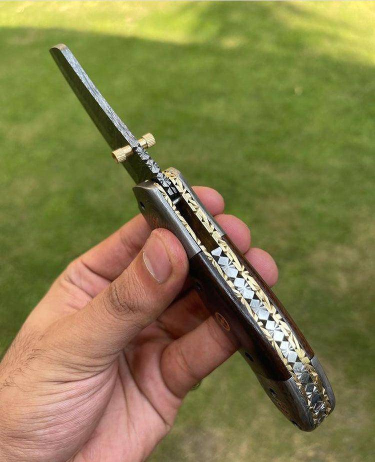 Damascus folding pocket knife by cskforged with a textured blade and ergonomic handle, displayed open on a neutral background.