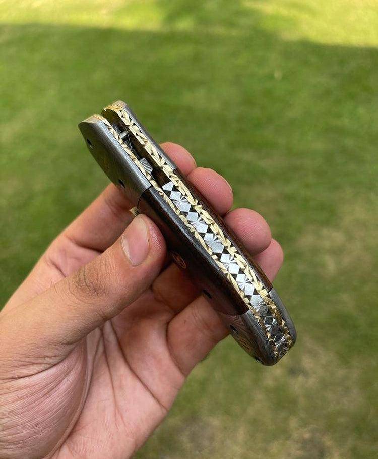 Damascus folding pocket knife by cskforged with a patterned blade and ergonomic handle, suitable for everyday carry.