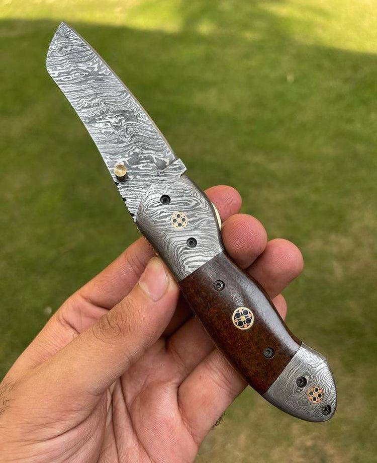 Damascus folding EDC pocket knife by cskforged with a patterned blade and ergonomic handle, displayed open on a neutral background.