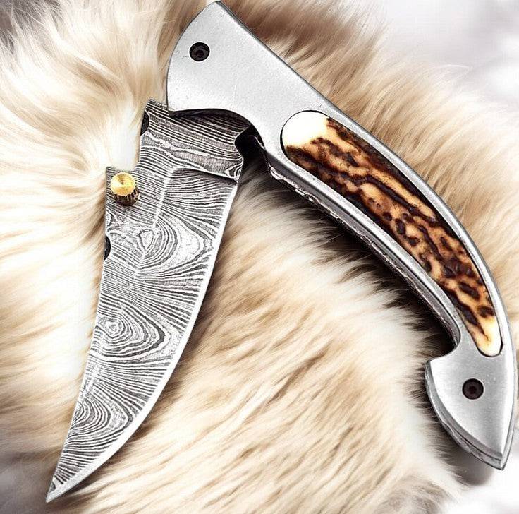 Handmade Damascus pocket knife with stag horn handle and 3-inch blade, featuring intricate Damascus steel pattern.