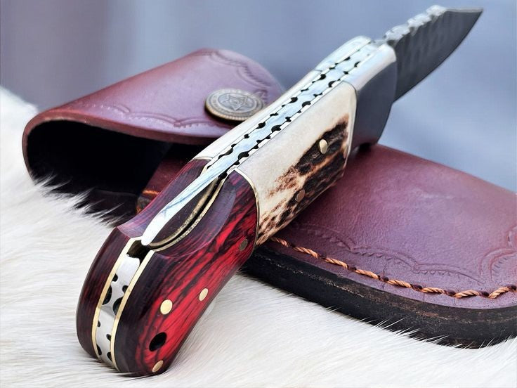 Handmade Damascus pocket knife with stag and Pakka wood handle, featuring a polished Damascus steel blade.