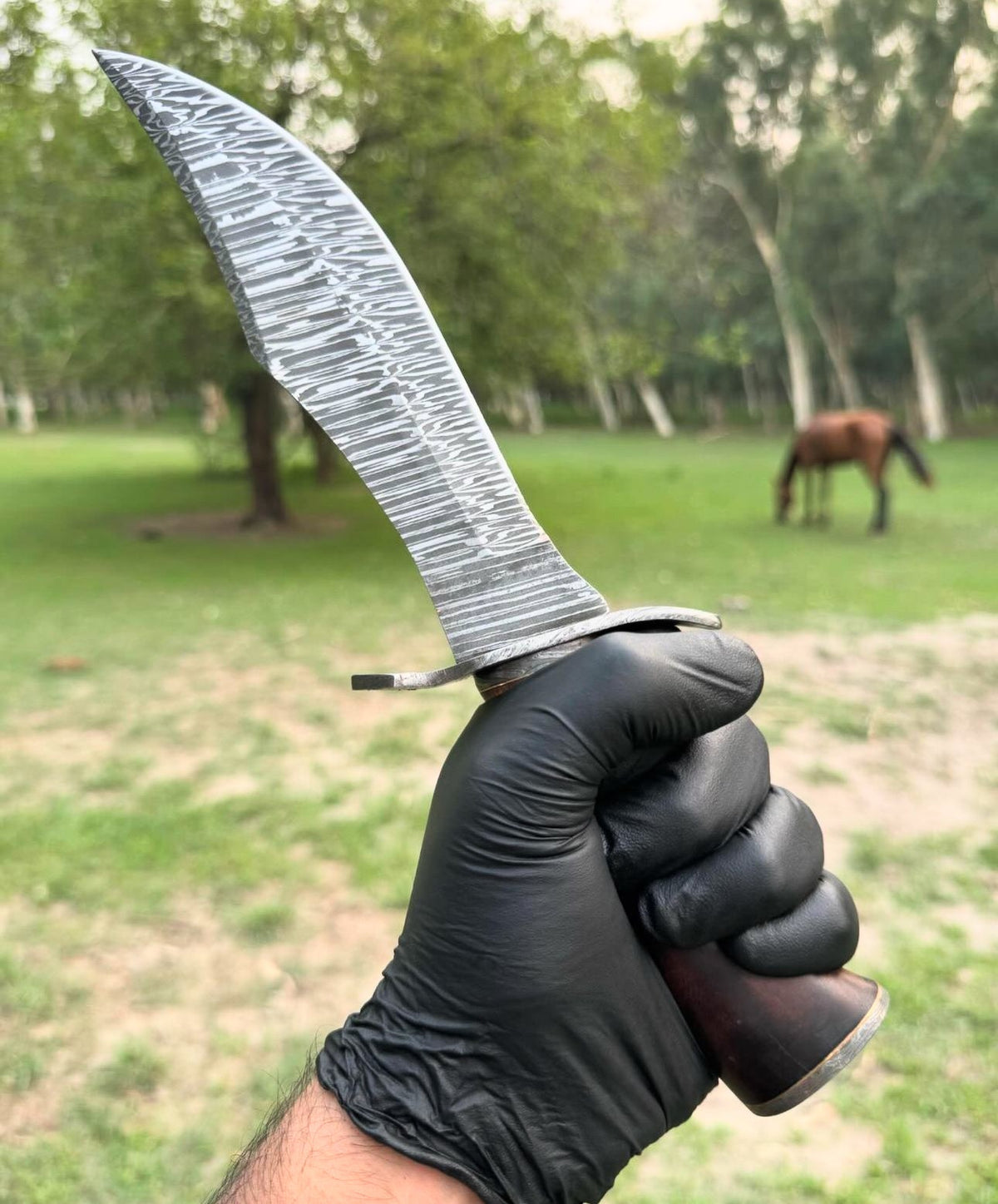 Custom handmade Damascus steel hunting Bowie knife with a leather handle and intricate pattern, perfect for outdoor hunting.