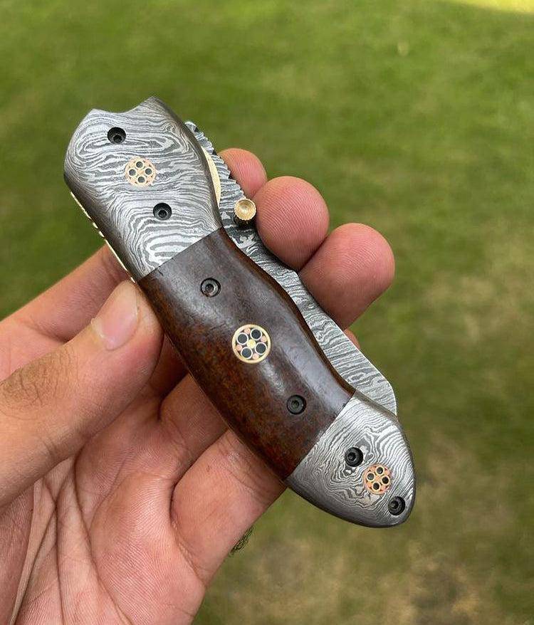 Damascus folding EDC pocket knife by cskforged with a patterned steel blade and ergonomic handle, displayed open.