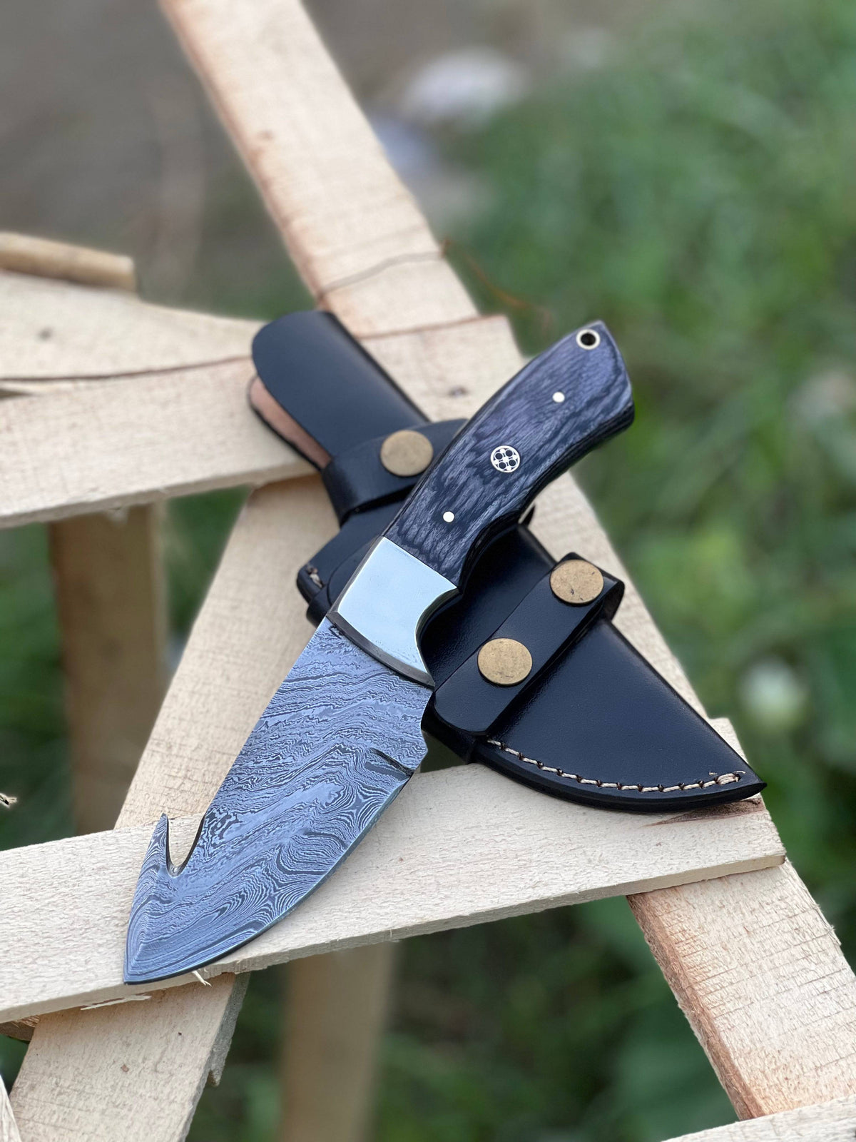 Handmade Damascus steel Guthook skinning knife by Knives Gear Garage, showcasing a textured blade and ergonomic handle.