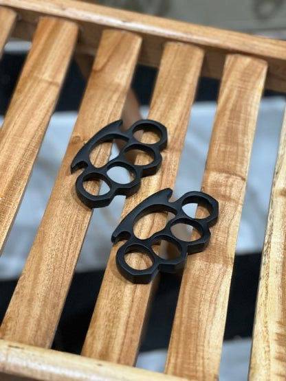 Pair of black hand-casted knuckles by CSK Forged, showcasing durable metal construction with a sleek, polished finish.
