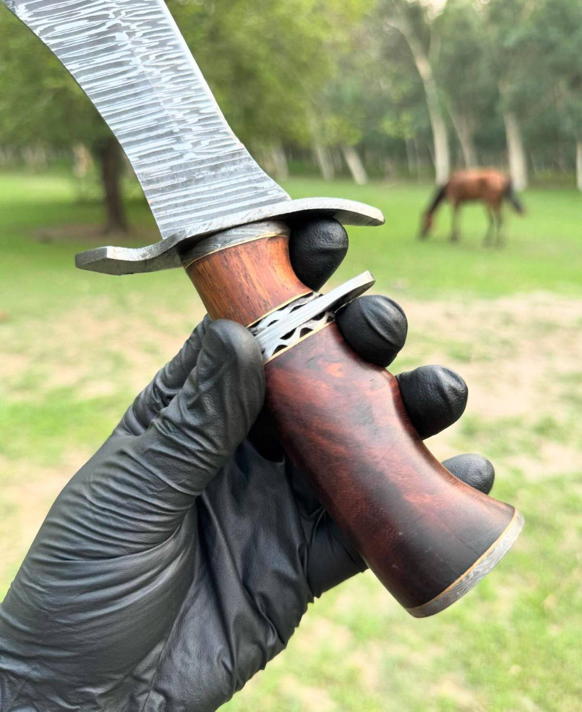 Custom handmade Damascus steel hunting Bowie knife with a detailed leather sheath and polished blade by Knives Gear Garage.