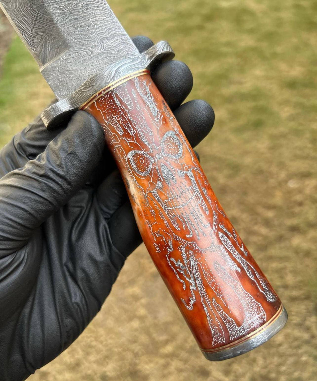 Handmade Damascus hunting knife with skull handle by cskforged, featuring a sharp blade suitable for camping and outdoor use.
