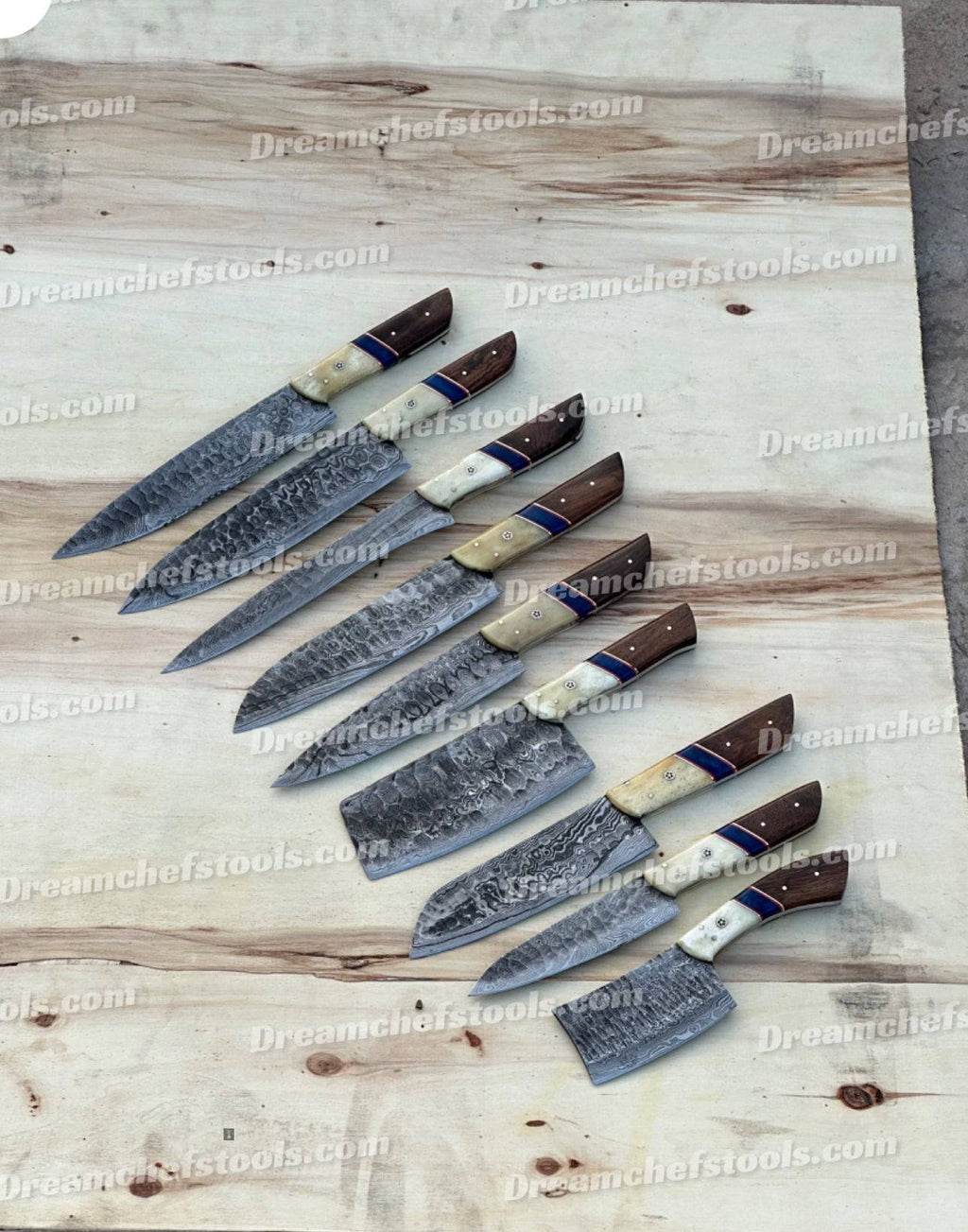 Handmade kitchen knife set by Knives Gear Garage with stainless steel blades and wooden handles on a countertop.