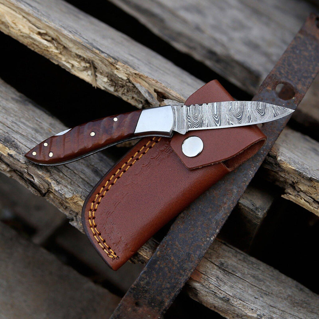 Handmade Damascus steel pocket knife with rosewood handle, steel bolster, and leather sheath, 3-inch overall length.