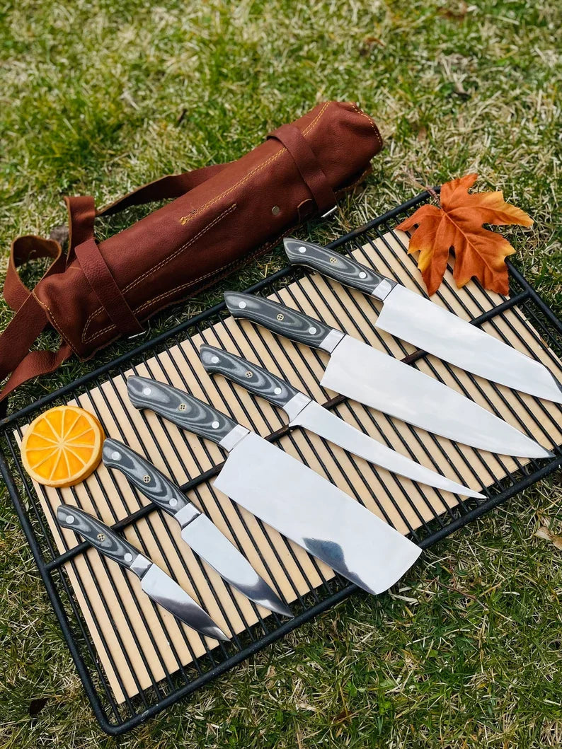 Custom handmade J2 Steel kitchen knife set by Knives Gear Garage featuring G10 handles, steel bolsters, and a leather roll kit.