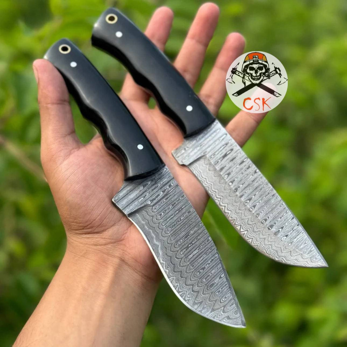 Pair of premium hand-forged Damascus steel hunting knives with ergonomic black handles by cskforged, featuring high-performance blades.