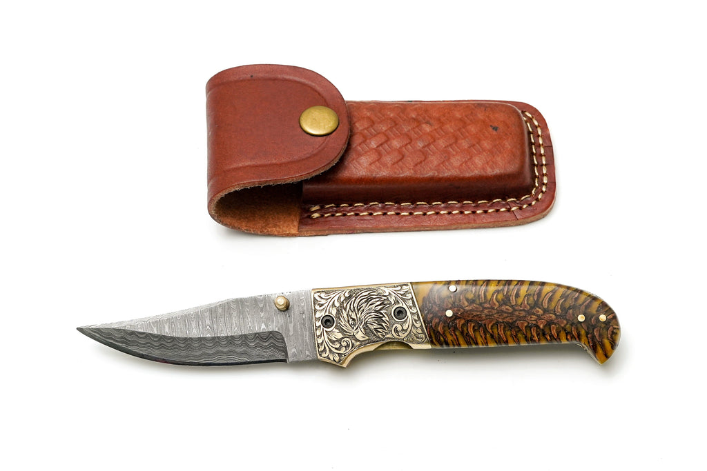 Custom Damascus steel clip point folding knife with engraved eagle bolster and amber pine cone handle by Titan International K.
