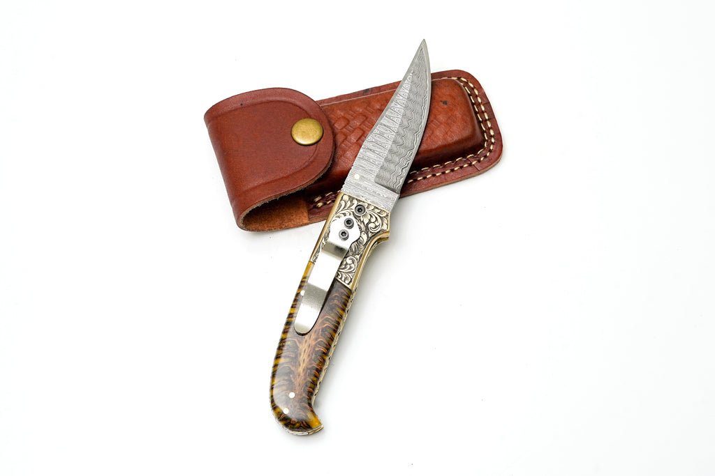 Custom Damascus steel clip point folding knife with engraved eagle bolster and amber pine cone handle by Titan International K.