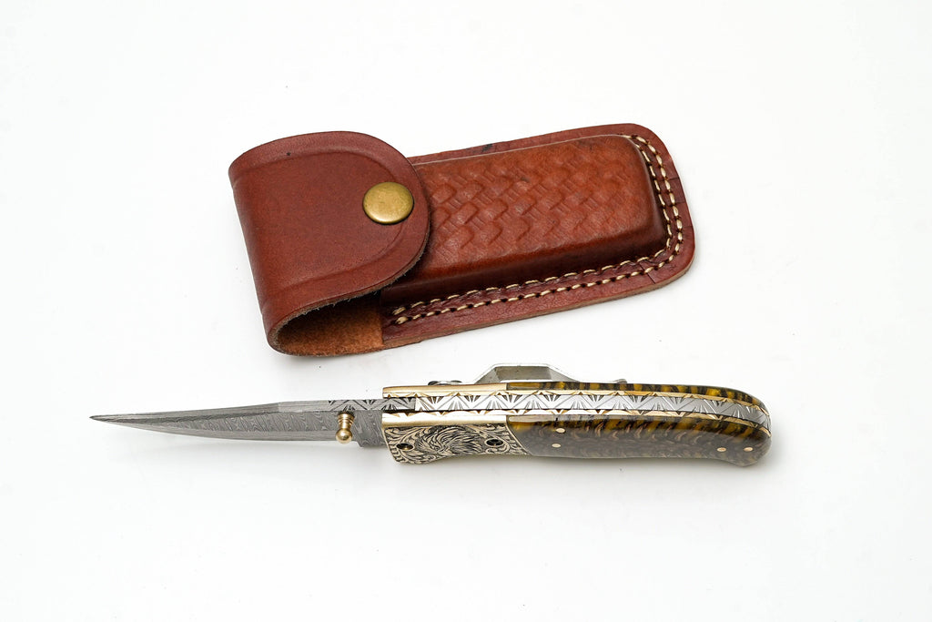 Custom Damascus steel clip point folding knife with engraved eagle bolster and amber pine cone handle by Titan International K.