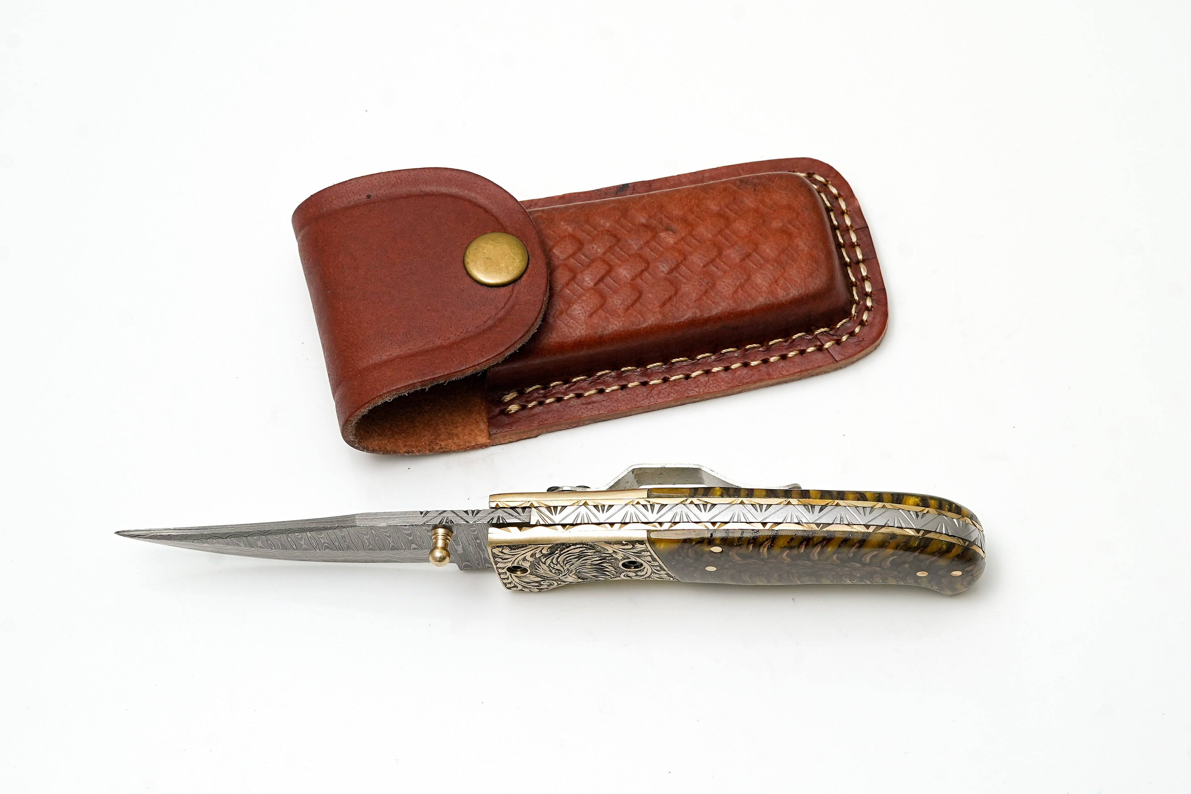 Custom Damascus steel clip point folding knife with engraved eagle bolster and amber pine cone handle by Titan International K.