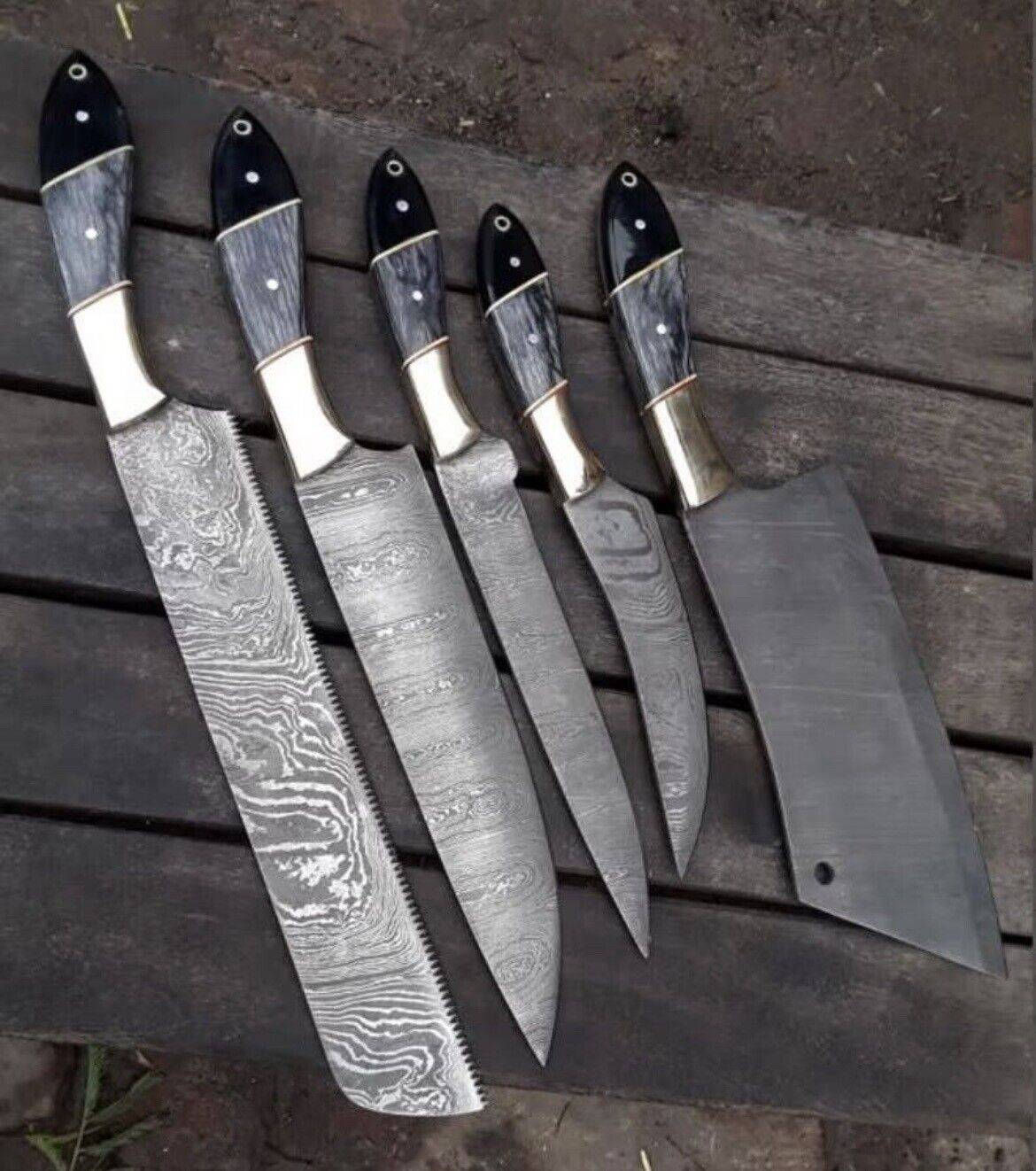 Custom handmade Damascus steel kitchen knives set with pakkawood and buffalo horn handles, resting in a leather sheath.