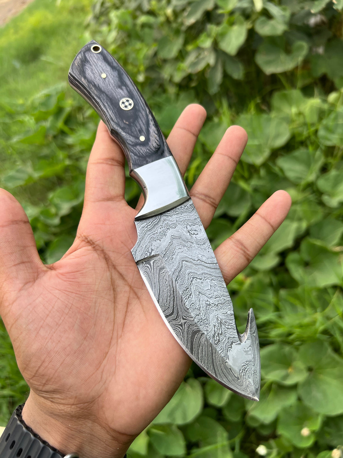 Handmade Damascus steel Guthook skinning knife with custom handle, crafted by Knives Gear Garage for outdoor hunting and skinning tasks.