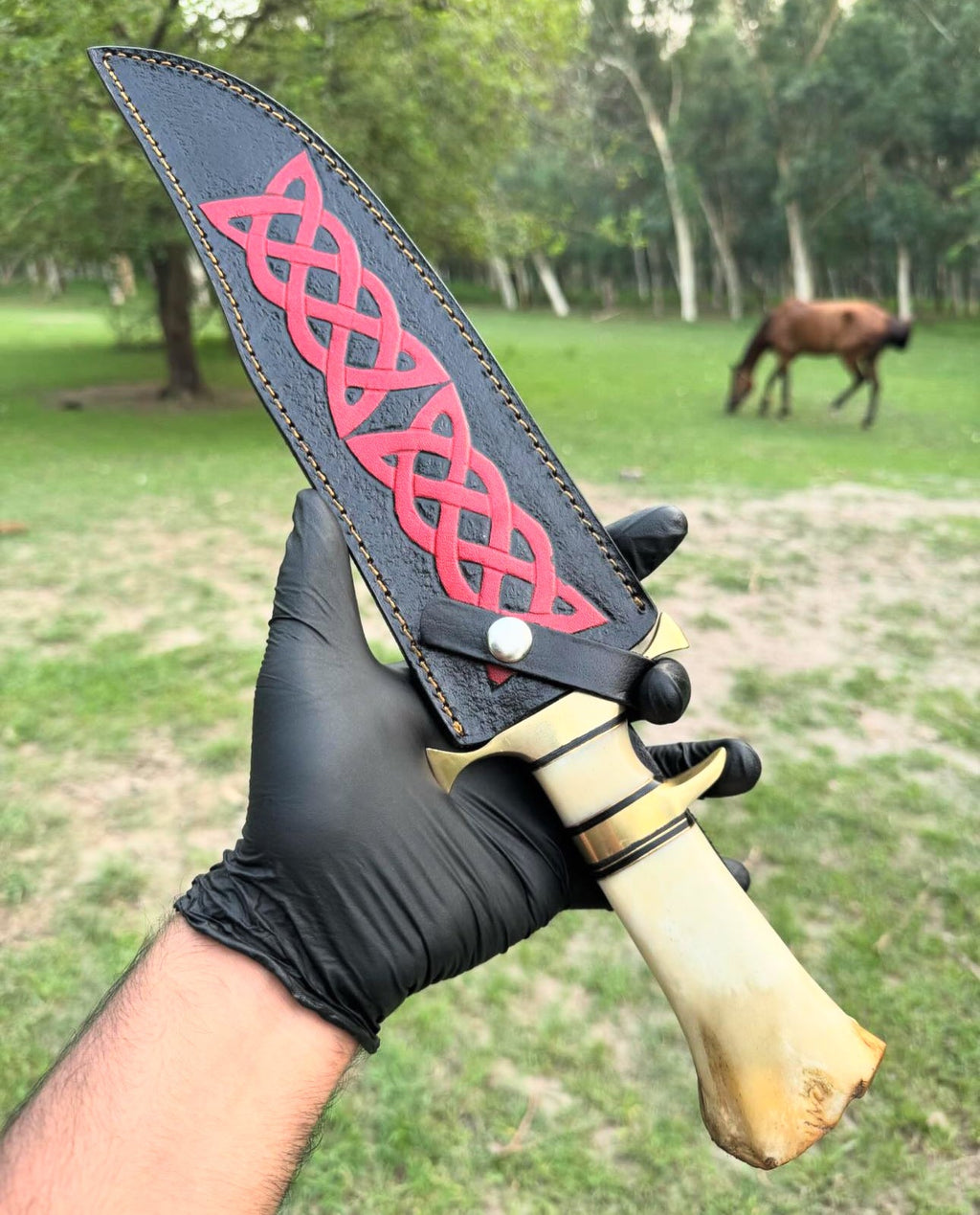 Handmade 16-inch Damascus steel Bowie knife with brass guard, camel bone handle, and leather sheath by Knives Gear Garage.