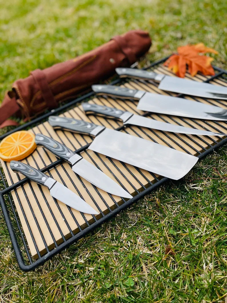 Custom handmade J2 Steel kitchen knife set by Knives Gear Garage featuring G10 handles, steel bolsters, and a leather roll kit.