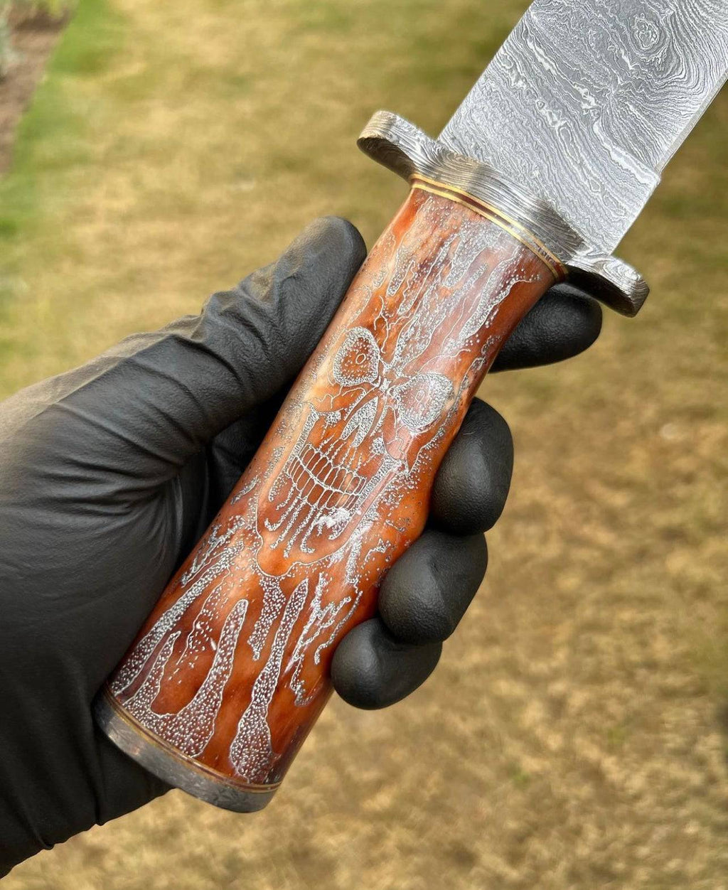 Handmade Damascus hunting knife with skull handle by cskforged, featuring a sharp blade suitable for camping and outdoor use.