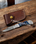 Damascus folding pocket knife with back lock and leather sheath, crafted by cskforged, featuring intricate Damascus steel pattern.