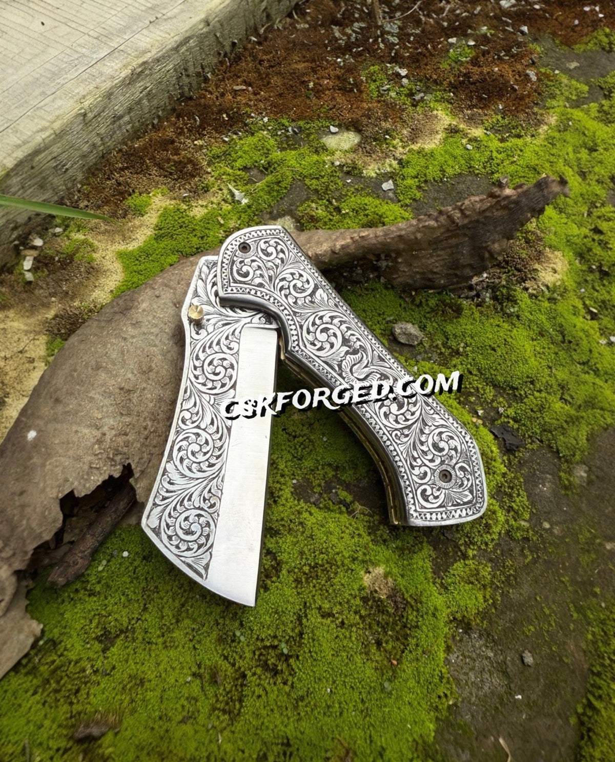 Hand-engraved scrollwork pocket knife by cskforged with intricate engraved patterns and a polished metal finish.