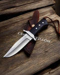 CSKforged Loveless Style D2 Steel hunting knife with black Micarta handle and leather sheath, full view of the outdoor-ready knife.