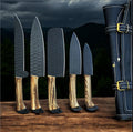 Handcrafted kitchen knives set with forged steel blades and olive wood handles, displayed inside a leather case.