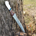 Handmade Damascus steel fillet knife with camel bone and rosewood handle, shown with leather sheath for fishing.