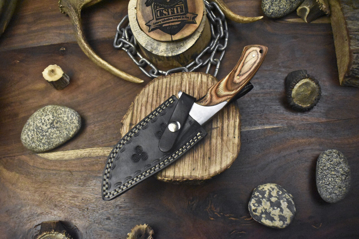 Handmade J2 steel hunting knife with a 10-inch pakkawood handle, steel bolster, and leather sheath for outdoor use.