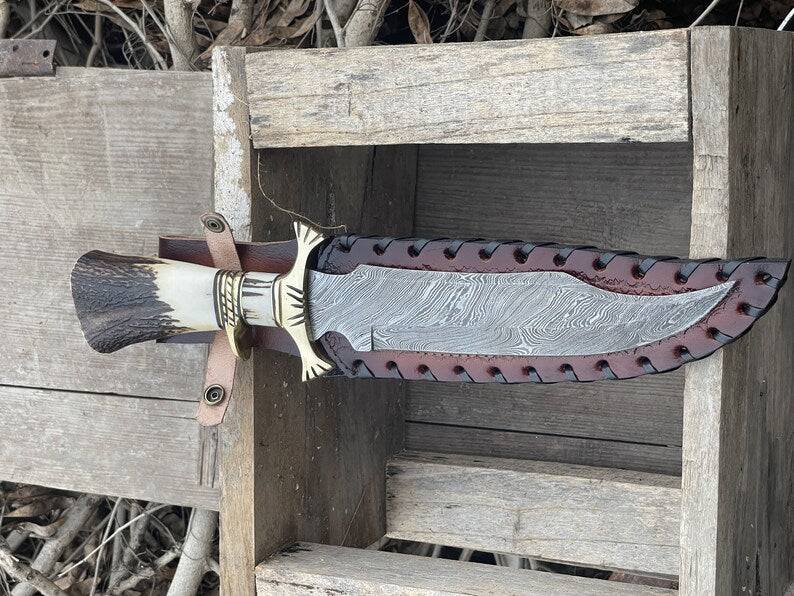 Handmade Bowie knife with a polished blade and leather handle from Knives Gear Garage, displayed on a wooden surface.