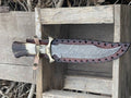 Handmade Bowie knife with a polished blade and leather handle from Knives Gear Garage, displayed on a wooden surface.
