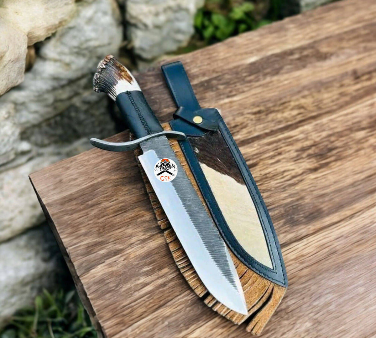Cskforged Rugged Frontier Knife with high carbon steel blade, stag handle, and Western leather sheath on display.